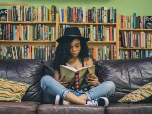 woman reading a book while sitting on black leather 3-seat couch